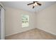 Bright, neutral bedroom features tile floor, a ceiling fan, and a window with backyard views at 10106 Tolman Dr, Hudson, FL 34667