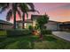 Charming single-story home with a well-manicured lawn and lush landscaping at sunset at 10106 Tolman Dr, Hudson, FL 34667