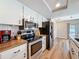 Modern kitchen featuring stainless steel appliances, white cabinets, butcher block countertops, and wood-look floors at 10478 Laval St, Spring Hill, FL 34608