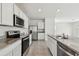 Bright kitchen featuring granite countertops, a stainless steel refrigerator, and white cabinets at 10823 Penny Gale Loop, San Antonio, FL 33576