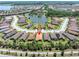 An aerial view of a well-maintained community with lush landscaping, a pond, and several homes with terra cotta roofs at 11325 Juglans Dr, Odessa, FL 33556