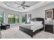 The main bedroom features a tray ceiling, large windows with outside views, and modern furnishings at 11325 Juglans Dr, Odessa, FL 33556
