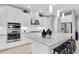 This kitchen showcases an island with seating, stainless appliances, white cabinets, and sleek pendant lights at 11325 Juglans Dr, Odessa, FL 33556