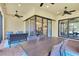 Covered patio area with a dark wood dining table, wicker chairs, a love seat and open sliding doors to the home's interior at 11325 Juglans Dr, Odessa, FL 33556