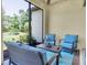 A covered patio with outdoor seating includes a wicker love seat, two chairs, a small table, and a blue and white rug at 11325 Juglans Dr, Odessa, FL 33556