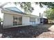 Backyard view with a white house, windows, a screened in porch, and grass with leaves at 12210 Quail Run Row, Hudson, FL 34667