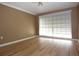 Bedroom featuring neutral walls, wood-look floors, and a large window with blinds at 12210 Quail Run Row, Hudson, FL 34667