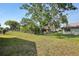 Large grassy backyard featuring a chain-link fence, mature trees, and ample space for outdoor activities at 12906 Sandburst Ln, Hudson, FL 34667