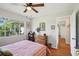 Bright bedroom with a window offering scenic views, a ceiling fan, and wood floors at 12906 Sandburst Ln, Hudson, FL 34667