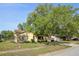 Landscaped front yard and home with a large tree providing shade at 12906 Sandburst Ln, Hudson, FL 34667