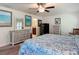 Cozy bedroom with ceiling fan, dressers, artwork, and ensuite bathroom access for added convenience at 13111 Precept Way, Hudson, FL 34669