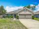 Charming single Gathering home showcasing a well-maintained lawn, mature landscaping, and an attached two car garage at 13111 Precept Way, Hudson, FL 34669
