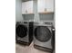 Modern laundry room featuring side by side washer and dryer, white cabinets, and neutral walls at 13205 Arkendale St, Spring Hill, FL 34609