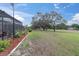 Expansive backyard with manicured landscaping and screened enclosure at 13524 Knotty Ln, Hudson, FL 34669