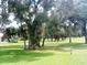Expansive backyard view showcasing mature trees providing shade and a glimpse of the home's sunroom at 13524 Knotty Ln, Hudson, FL 34669
