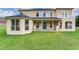 Expansive backyard featuring lush green grass, lion statues, and the home's exterior with large windows at 15906 Prince William Pl, Odessa, FL 33556
