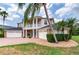 Suburban two-story home featuring a three-car garage, lush landscaping, and brick-paved driveway at 15906 Prince William Pl, Odessa, FL 33556