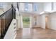 Bright living room showcasing a staircase, large windows with white curtains, and wood-look flooring at 15906 Prince William Pl, Odessa, FL 33556
