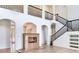 Open-concept living room with a fireplace, staircase with black railings, and arched doorways at 15906 Prince William Pl, Odessa, FL 33556