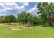 A serene view of a pond surrounded by lush trees and a well-maintained grassy area at 15906 Prince William Pl, Odessa, FL 33556