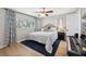 This primary bedroom features blue patterned curtains, a ceiling fan, and light wood flooring at 1700 Beachway Ln, Odessa, FL 33556