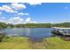 Waterfront view of lake and covered dock/boat house on a clear, sunny day with some clouds at 1700 Beachway Ln, Odessa, FL 33556