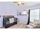 This cozy bedroom features ample light, a dark-wood crib, and comforting decorative features at 18061 Glastonbury Ln, Land O Lakes, FL 34638