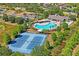 Aerial view of neighborhood amenities including tennis courts, pool, playground and clubhouse near lush trees and landscaping at 18061 Glastonbury Ln, Land O Lakes, FL 34638