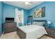 A comfortable bedroom with blue walls, TV, ceiling fan, and a bright window at 1810 Winsloe Dr, Trinity, FL 34655