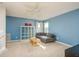 Bright living room with ceiling fan, plush grey couch, and a large storage shelf at 1810 Winsloe Dr, Trinity, FL 34655