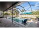Screened-in private pool area with a cool blue swimming pool, blue umbrella, and poolside seating at 1810 Winsloe Dr, Trinity, FL 34655