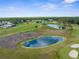 Scenic aerial view of lush golf course, mature trees, pristine ponds, and lovely neighborhood homes at 18209 Breland Dr, Hudson, FL 34667