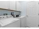Bright laundry room featuring white washer, dryer, cabinets, and a conveniently located doorway at 18209 Breland Dr, Hudson, FL 34667