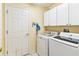 Laundry room with white washer, dryer, and storage cabinets at 18532 Myrtlewood Dr, Hudson, FL 34667