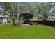 Spacious backyard with mature trees, an RV, and lawn equipment under a covered shelter at 18620 Gracie Lee St, Spring Hill, FL 34610