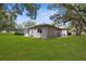 Expansive backyard featuring lush green grass, mature trees and partially screened in patio at 18620 Gracie Lee St, Spring Hill, FL 34610
