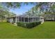 Large, well-maintained yard surrounded by mature trees, featuring an enclosed patio at 18620 Gracie Lee St, Spring Hill, FL 34610