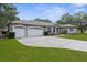 Charming gray home with three-car garage and stone accents set on a lush, well-maintained lawn at 18620 Gracie Lee St, Spring Hill, FL 34610