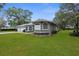 Charming gray home featuring stone accents, a manicured lawn, and mature landscaping at 18620 Gracie Lee St, Spring Hill, FL 34610
