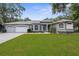 Inviting gray home with a manicured lawn, stone accents, arched windows, and a spacious three-car garage at 18620 Gracie Lee St, Spring Hill, FL 34610