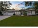 Inviting gray home with a manicured lawn, stone accents, arched windows, and a spacious three-car garage at 18620 Gracie Lee St, Spring Hill, FL 34610