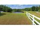 A pristine backyard with white fencing overlooks a tranquil pond surrounded by lush greenery on a sunny day at 19855 Ellendale Dr, Land O Lakes, FL 34638