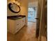 Bathroom vanity featuring white cabinetry, dark countertops, and framed round mirror at 210 S Hale Ave, Tampa, FL 33609