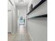 Bright hallway leading to the front door with decorative shelves and neutral tile flooring at 21167 Pleasant Plains Pkwy, Land O Lakes, FL 34637