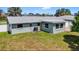 The home's backyard with a painted exterior, green grass, and surrounding fencing at 2175 Edythe Dr, Dunedin, FL 34698
