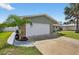 Side view of a single Gathering home showing the two-car garage, stone accents, and palm tree at 2175 Edythe Dr, Dunedin, FL 34698