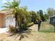 Side view of the home showcases a three-car garage and tropical landscaping along a fenced property line at 25352 Doredo Dr, Punta Gorda, FL 33955