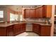 Functional kitchen featuring wood cabinets, granite counters, and stainless steel dishwasher at 3102 Lema Dr, Spring Hill, FL 34609