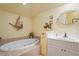 Bright bathroom features a soaking tub, tiled floors, and vanity with a white countertop and decor at 3431 Riderwood Dr, Dade City, FL 33523