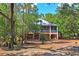 Charming elevated home featuring a metal roof, a screened porch, and stairs leading to the deck and yard at 3431 Riderwood Dr, Dade City, FL 33523